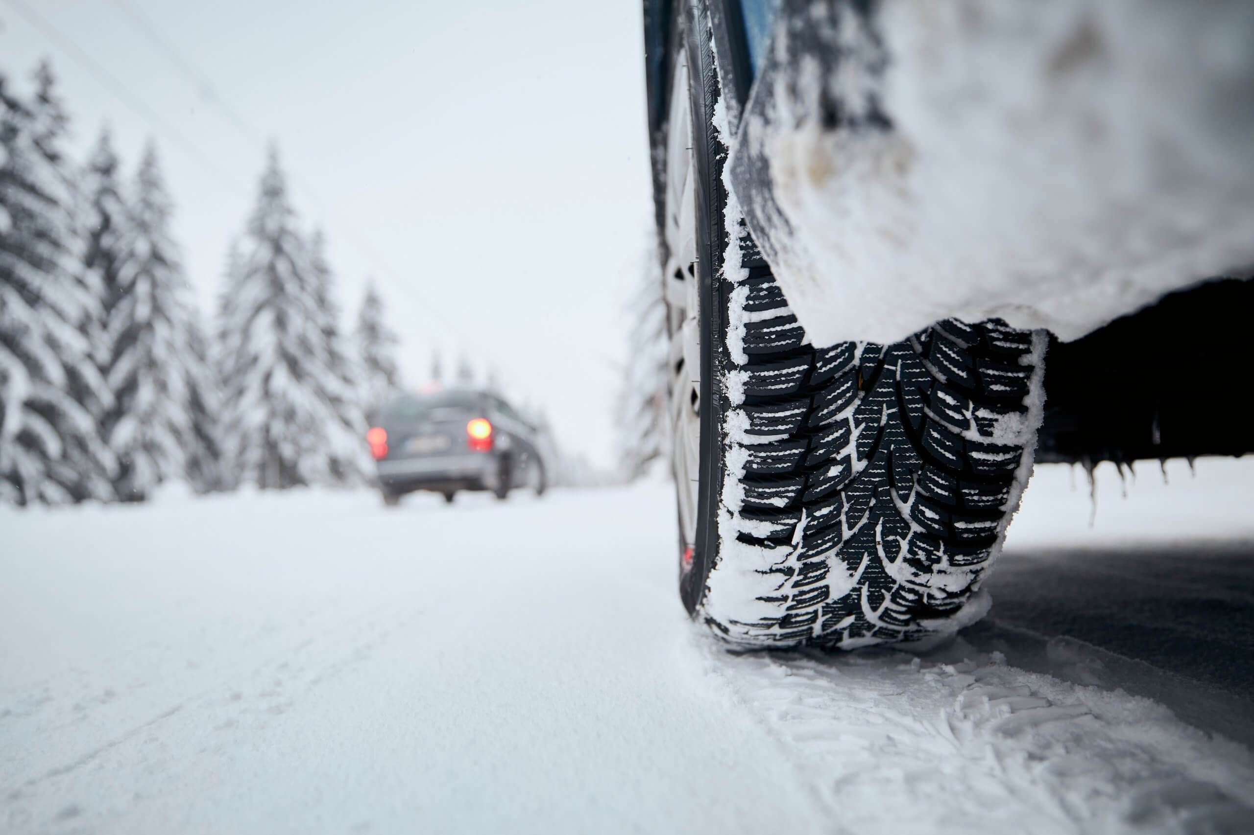 Close-up view of tire of car on snow covered and icy road. Themes safety and driving in winter.