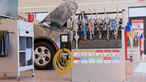 A picture of a car with it's hood open inside of an LOF Xpress Oil Change shop.