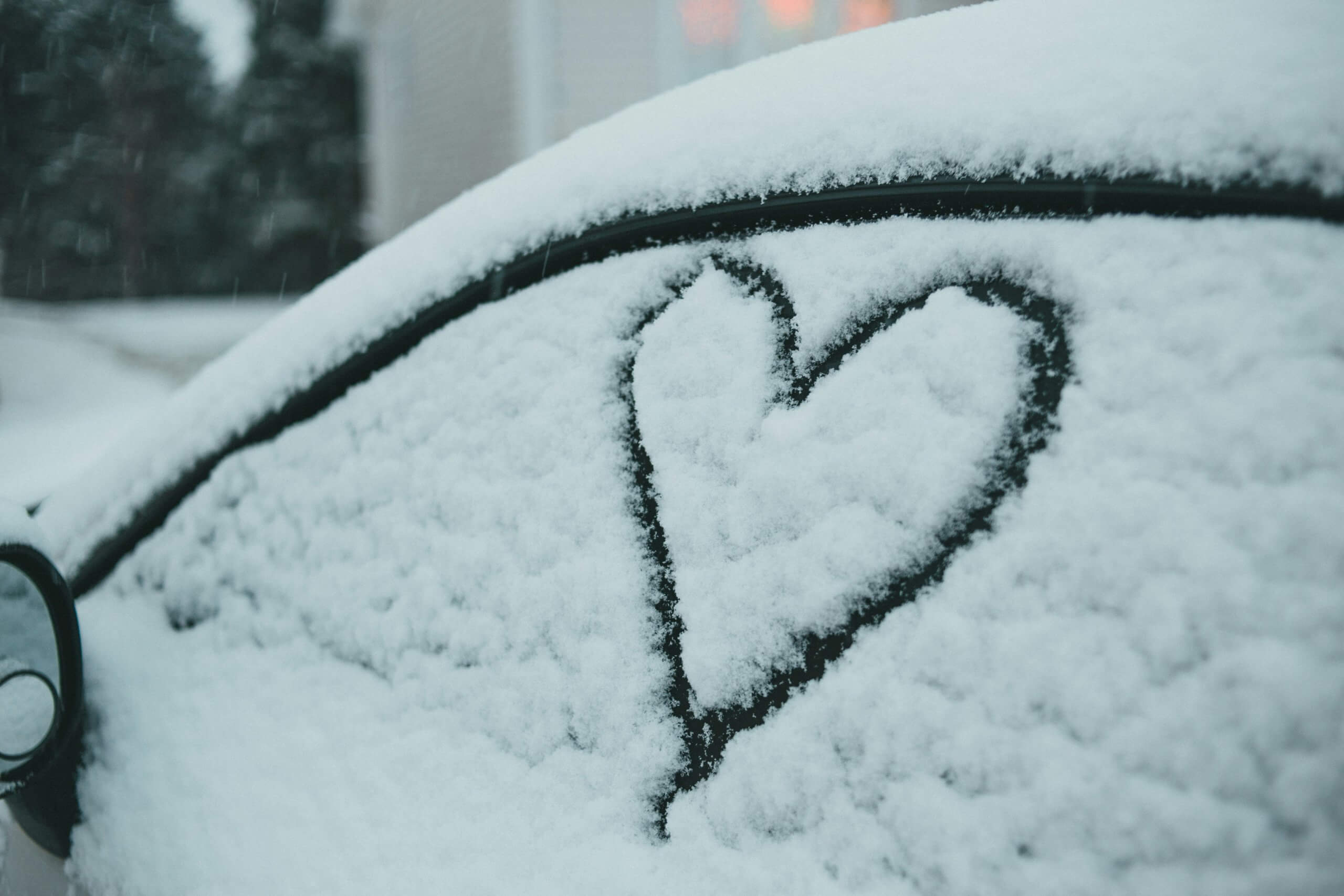 A picture of a heart drawn in the snow of a car window