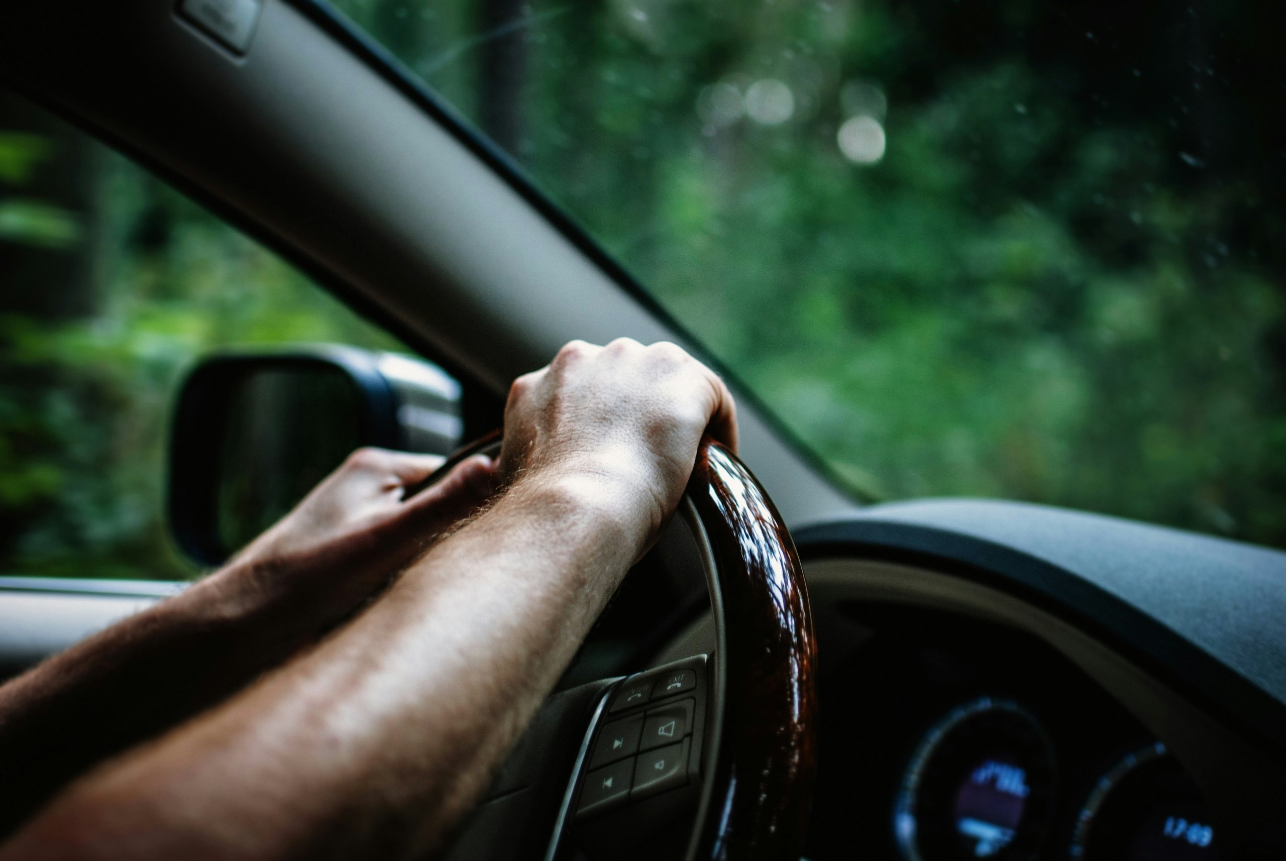 A person driving with their hand on the wheel.